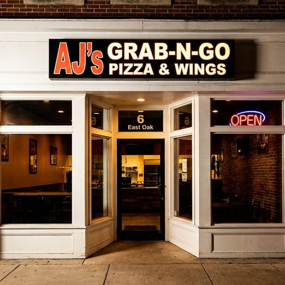 Exterior of AJ's Grab-N-Go Pizza & Wings, a brick building with a glowing "OPEN" sign.